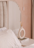 Neatly arranged room with a vase on a nightstand, pillows on a bed, and a neutral color scheme.